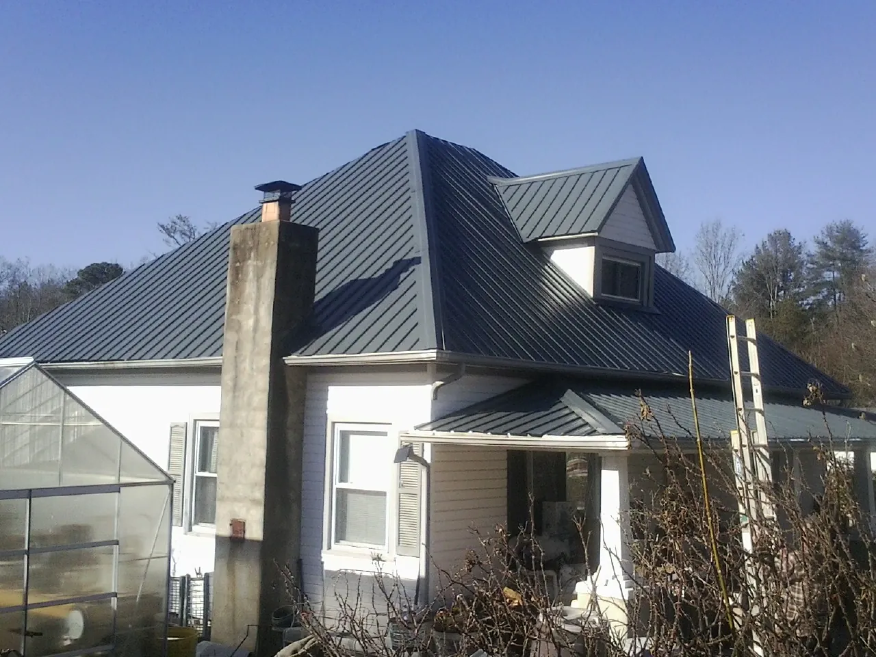 Dark blue standing seam metal roof on a white farmhouse with dormer — Slate & Tile Roof Repair by Roofing Brothers in Moapa