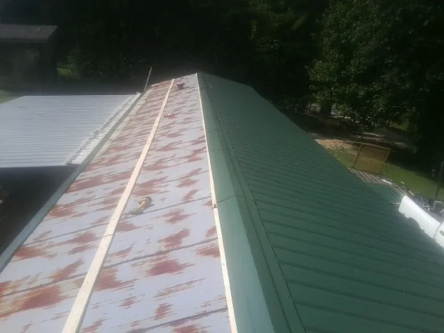 Old rusted panels beside newly installed green metal roofing — Wind Damage Roof Repair by Roofing Brothers in Moapa
