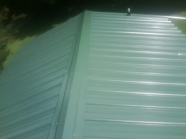 New green metal panels meeting at the ridge of a roof — Flat Roof Repair work by our crew in Moapa