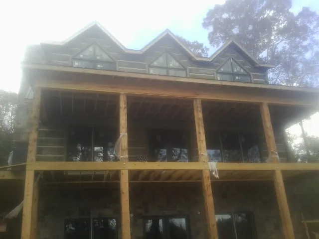 Dormers and porch framing on a large log home under construction — Roof Coating work by our crew in Moapa