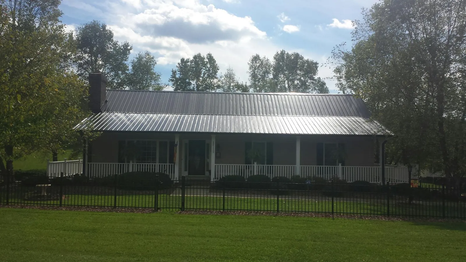 Gray metal roof on a brick ranch with a full width front porch — Gutter Guard Installation work by our crew in Moapa
