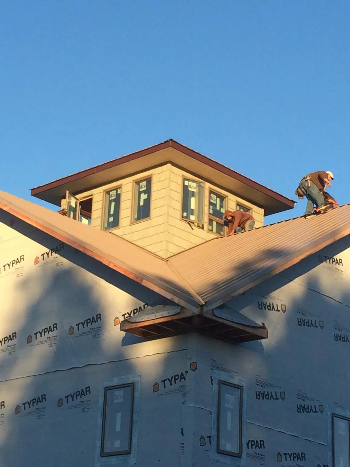 Roofers working around a rooftop cupola on a new metal roof at sunset — Roof Waterproofing in Moapa by Roofing Brothers